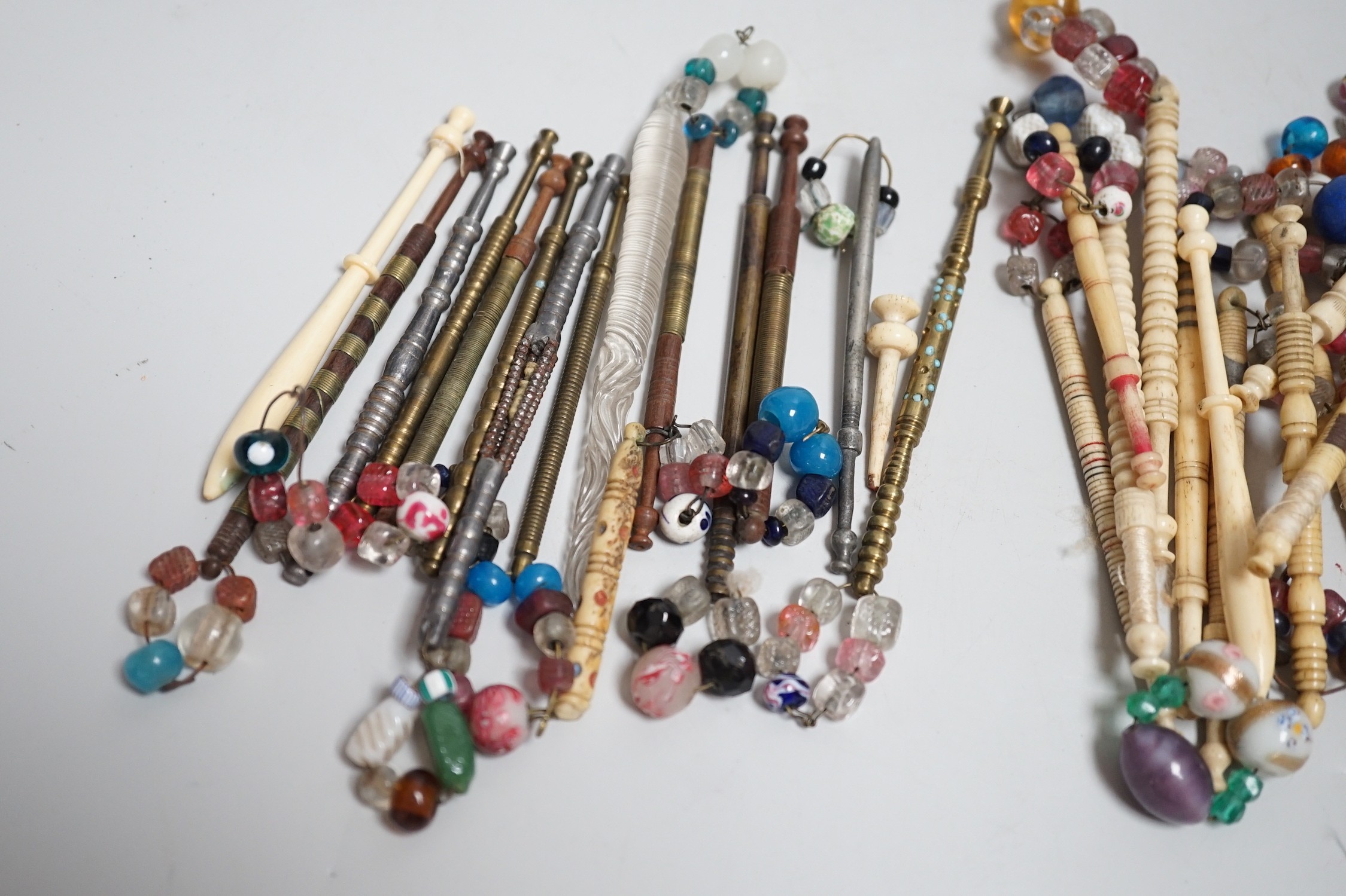 Twenty ornate 19th century turned bone and beaded topped lace bobbins and eleven ornately turned metal lace bobbins, glass bobbin and 3 broken bobbins (34)